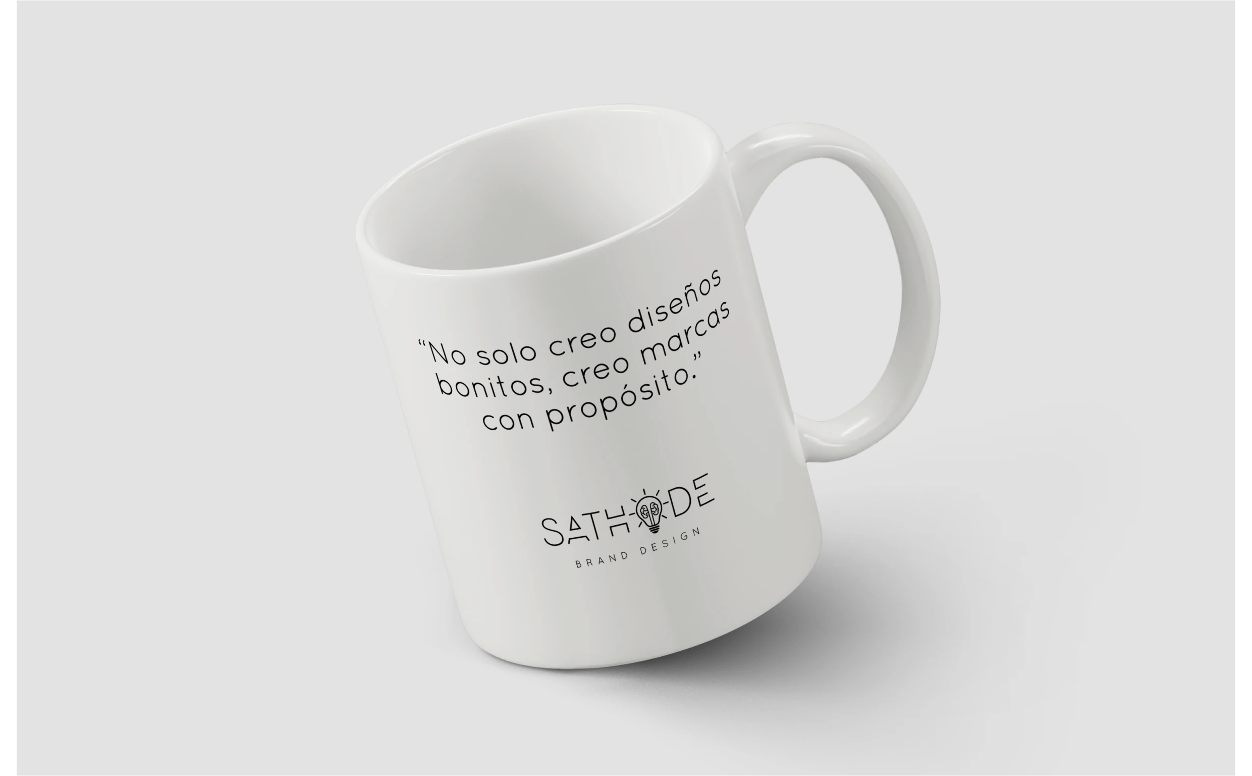 Imagen que muestra una taza de cerámica con el logo de SATHODE y el lema "No solo creo diseños bonitos, creo marcas con propósito". Esta taza refleja la filosofía de la marca en cuanto a la creación de marcas estratégicas, audaces y con un impacto duradero, perfecta para transmitir la misión de SATHODE a través de objetos de uso diario.