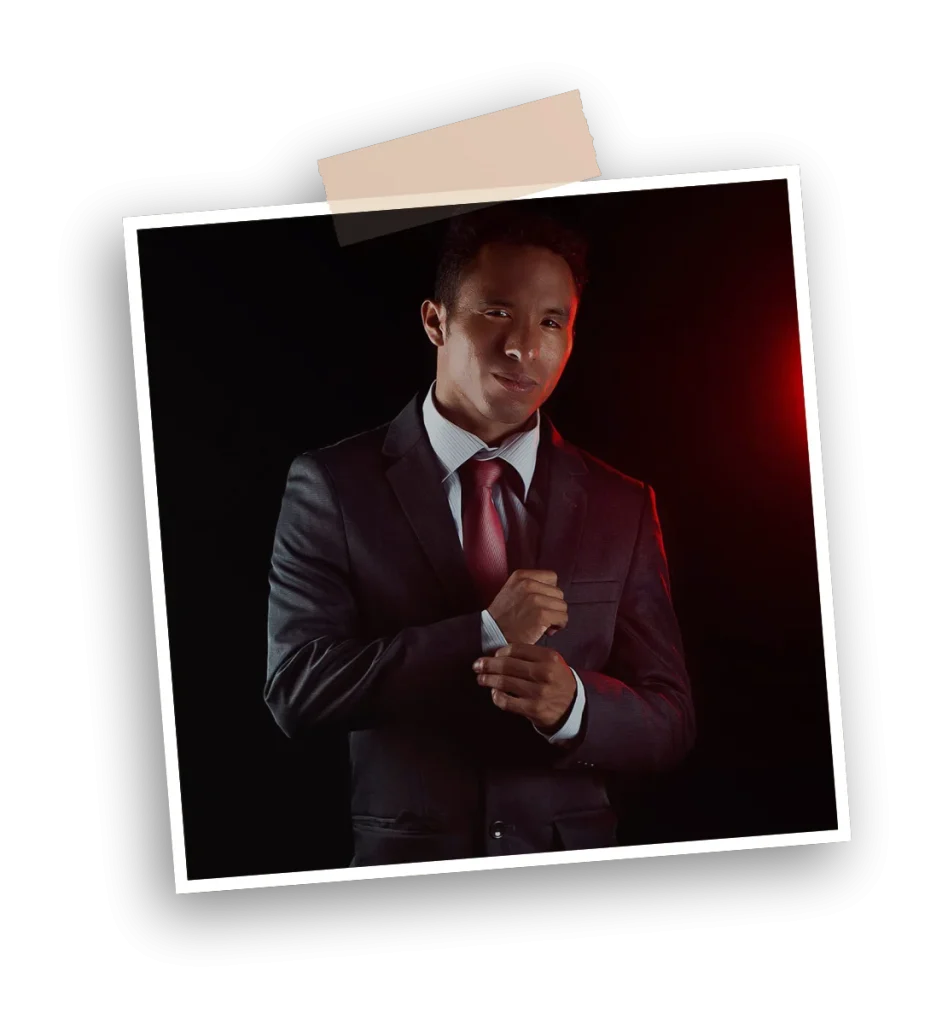 Retrato profesional en clave baja de edi marti diseñador gráfico con traje y corbata, fondo negro y acento de luz roja; imagen de marca para portafolio que proyecta confianza y elegancia. Servicios de diseño de logos e identidad visual y branding estratégico para marcas, emprendedores y empresas.
